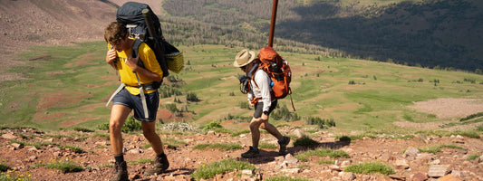 Two hikers with backpacks on a mountain trail