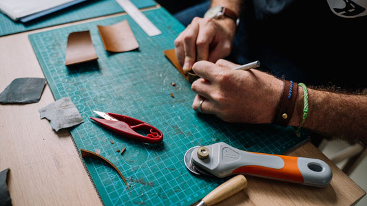 Artisan hands cutting and working genuine leather by hand in a workshop