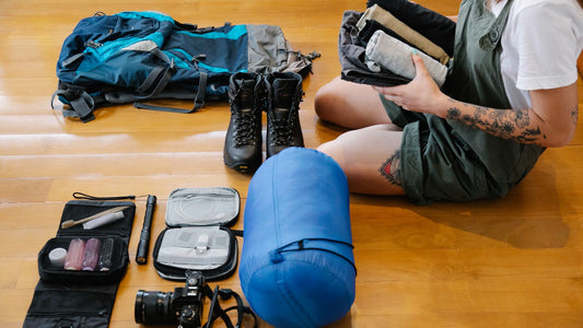 Folded clothes and gear being packed into an open backpack