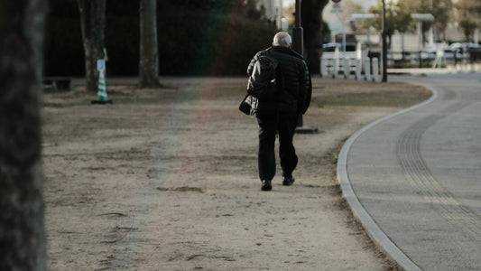 Person walking down a city street wearing a backpack while commuting