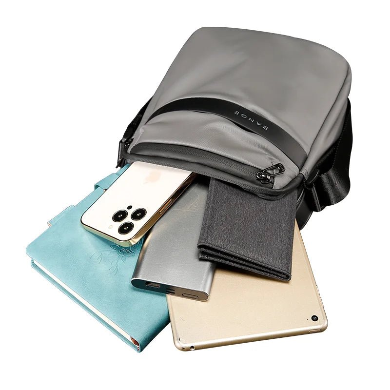 Nytra BANGE 2876 gray crossbody bag with contents including tablet, phone, and notebook spilling out to show capacity.